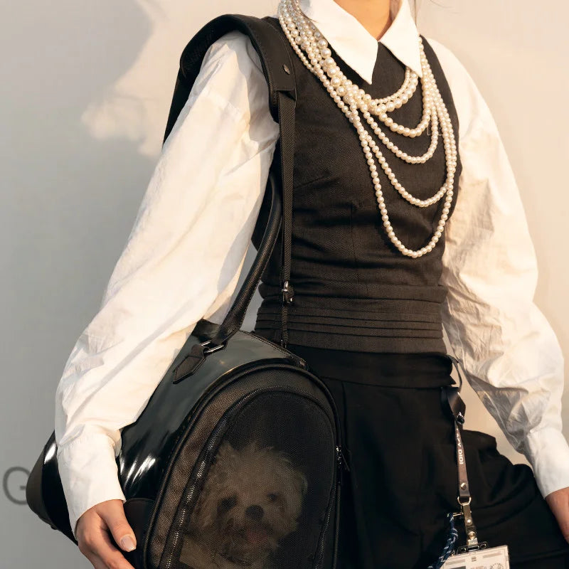Black patent leather pet carrier bag lifestyle shot with small white dog