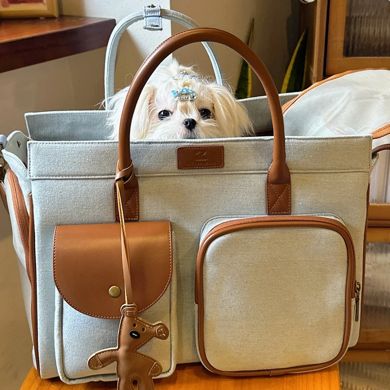 Light gray canvas pet carrier bag with brown leather trim, dog charm and multiple pockets