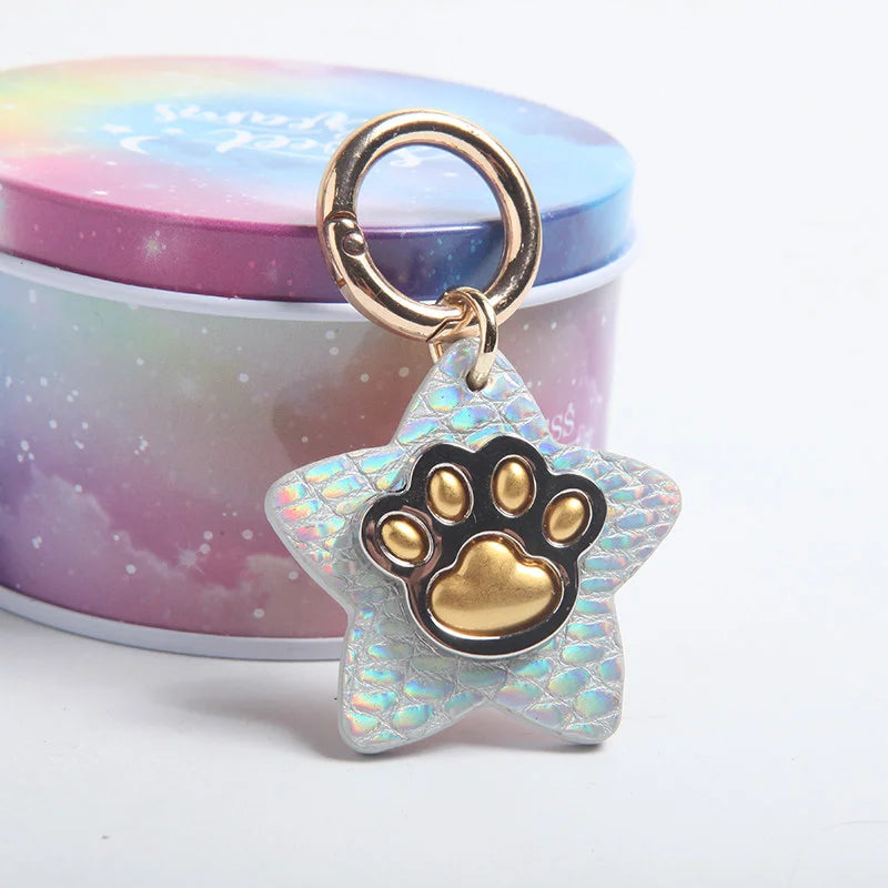 Holographic iridescent star pet tag with gold paw print on black background
