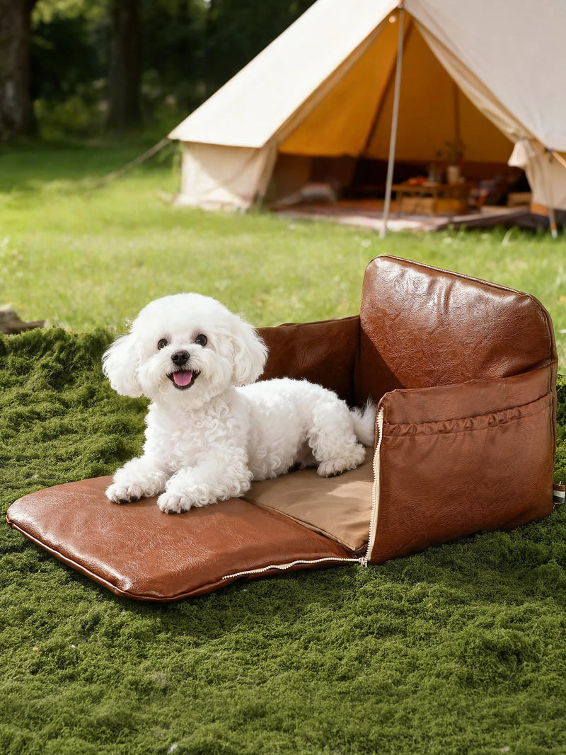 White fluffy dog sitting in brown leather pet carrier strapped to car seat