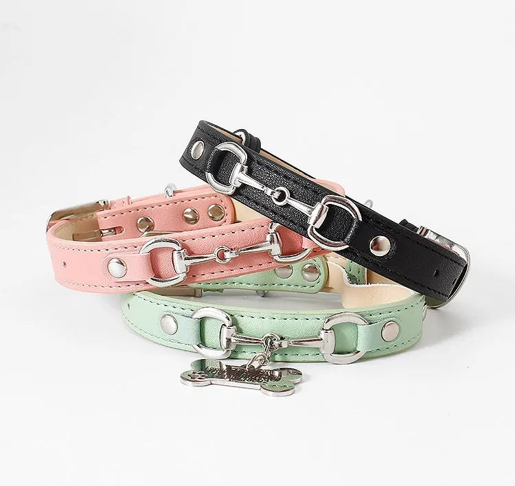 A stack of three stylish leather pet collars in pastel pink, classic black, and mint green, each featuring elegant silver horsebit hardware and metallic rivets, displayed against a clean white background.