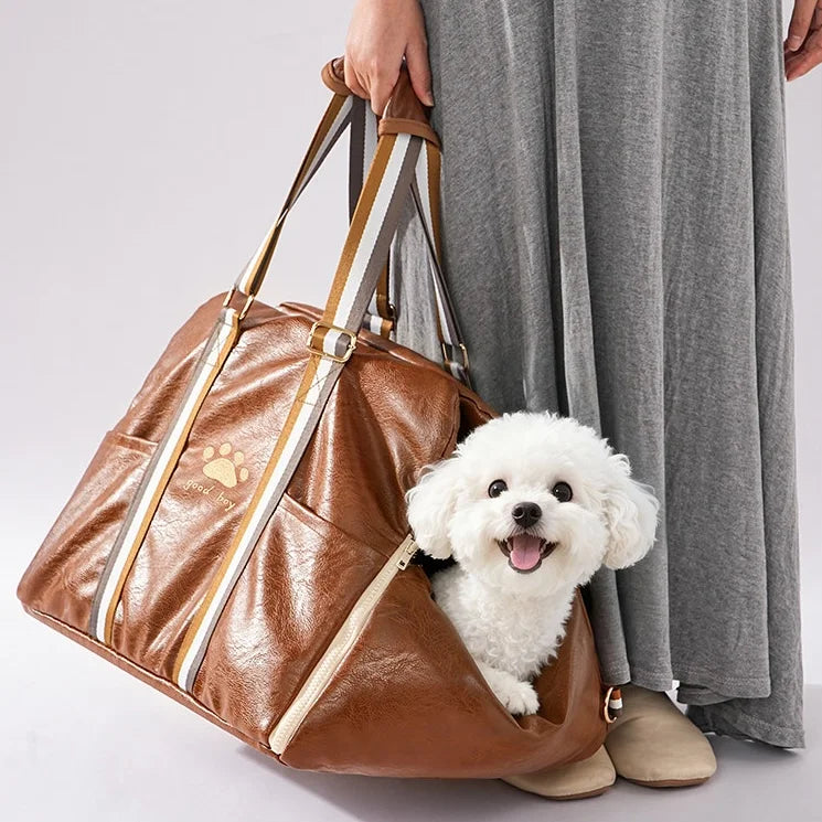Lifestyle photo of brown leather pet carrier being hand carried with white fluffy dog inside