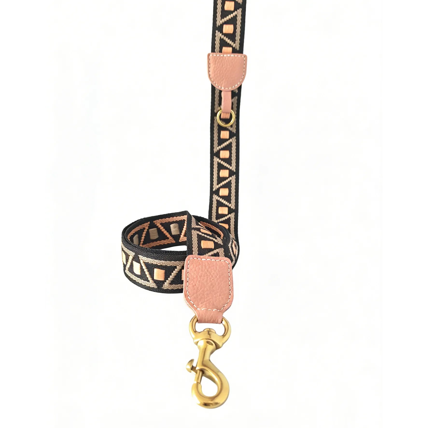 A stylish woven dog leash featuring a black and tan geometric triangle pattern with light pink pebbled leather accents and a brass-finished gold swivel snap hook against a solid white background.