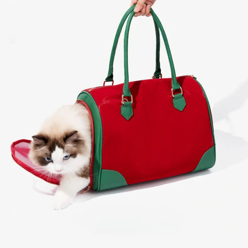Red and green canvas pet carrier bag held by hand, cylindrical Boston style