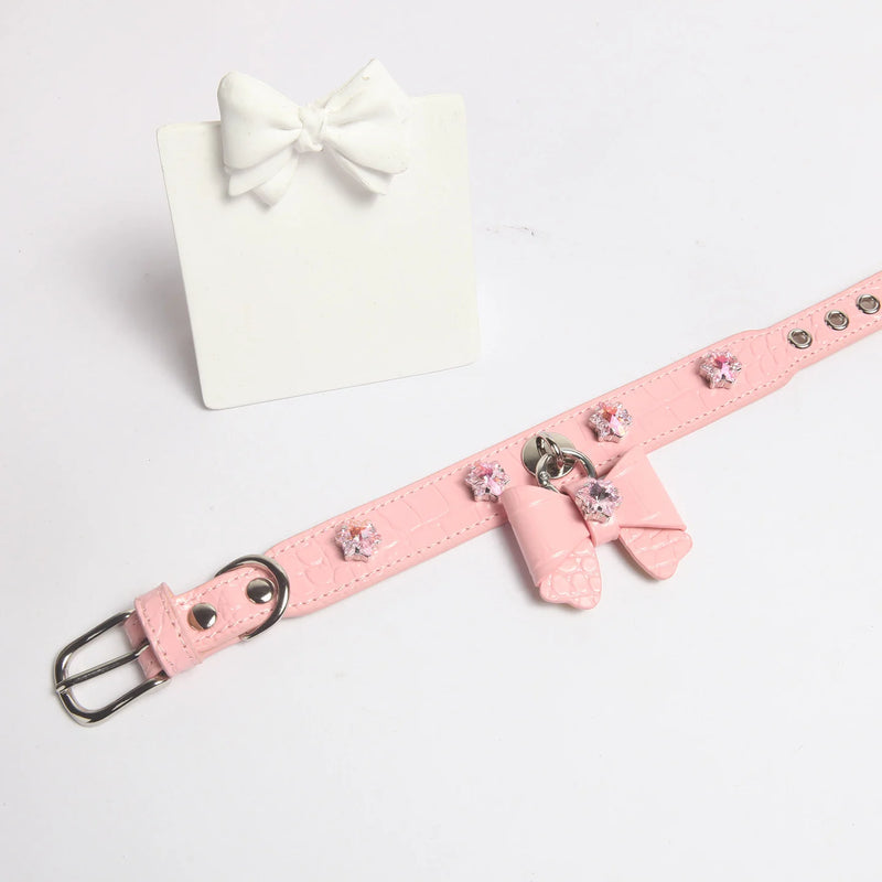 Dog wearing pink snowflake crystal bow collar showing silver hardware and crocodile texture